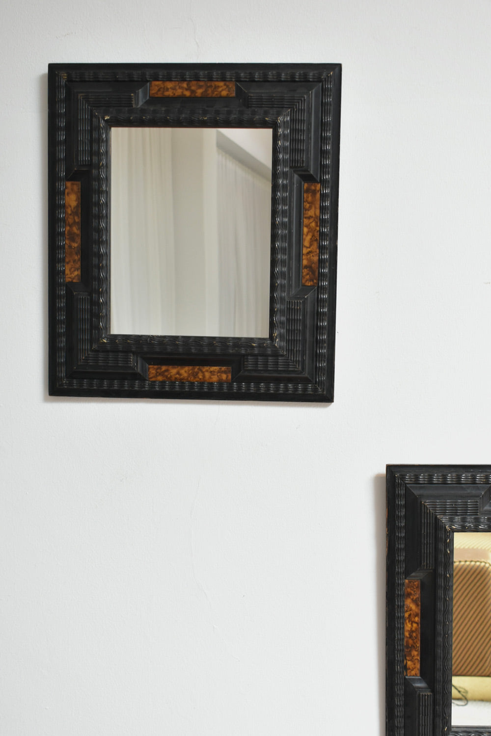 Pair of carved ebonised wood and trompe l'oeil turshell mirrors, XIXth c.
