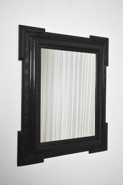 Carved ebonised wooden mirror, XIXth c.